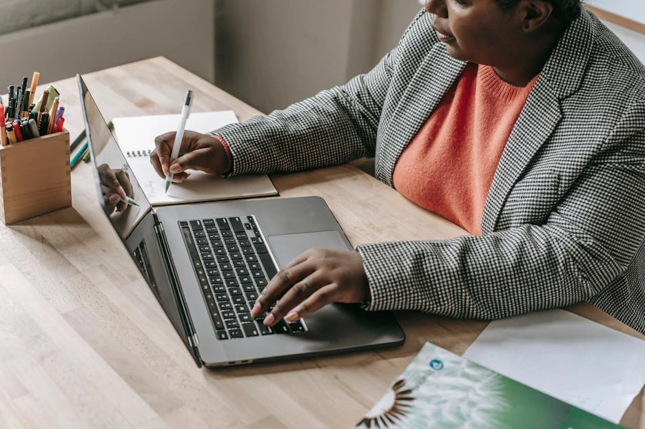 Professionista concentrato che prende appunti durante una lezione online sul suo laptop.